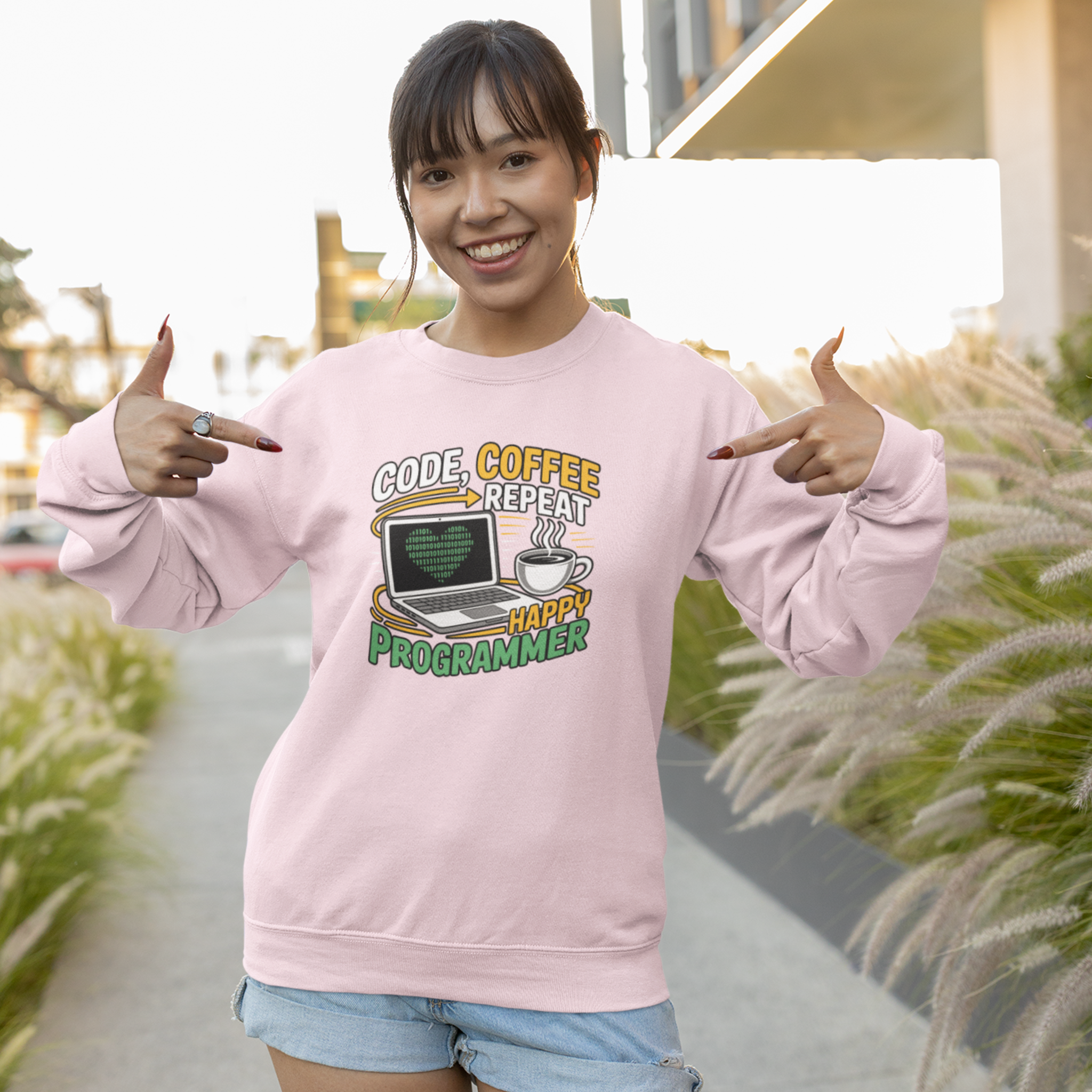 Person wearing a pink sweatshirt with a graphic design and text, standing outdoors.