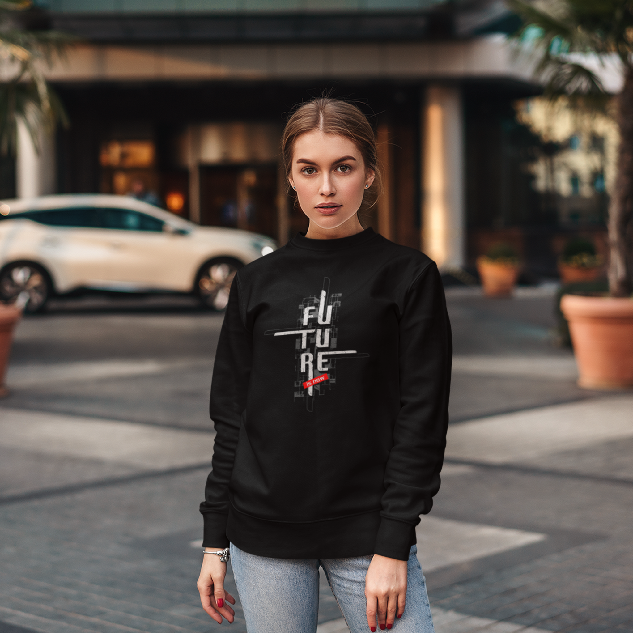 Woman wearing a black sweatshirt with text on it, standing on a street.