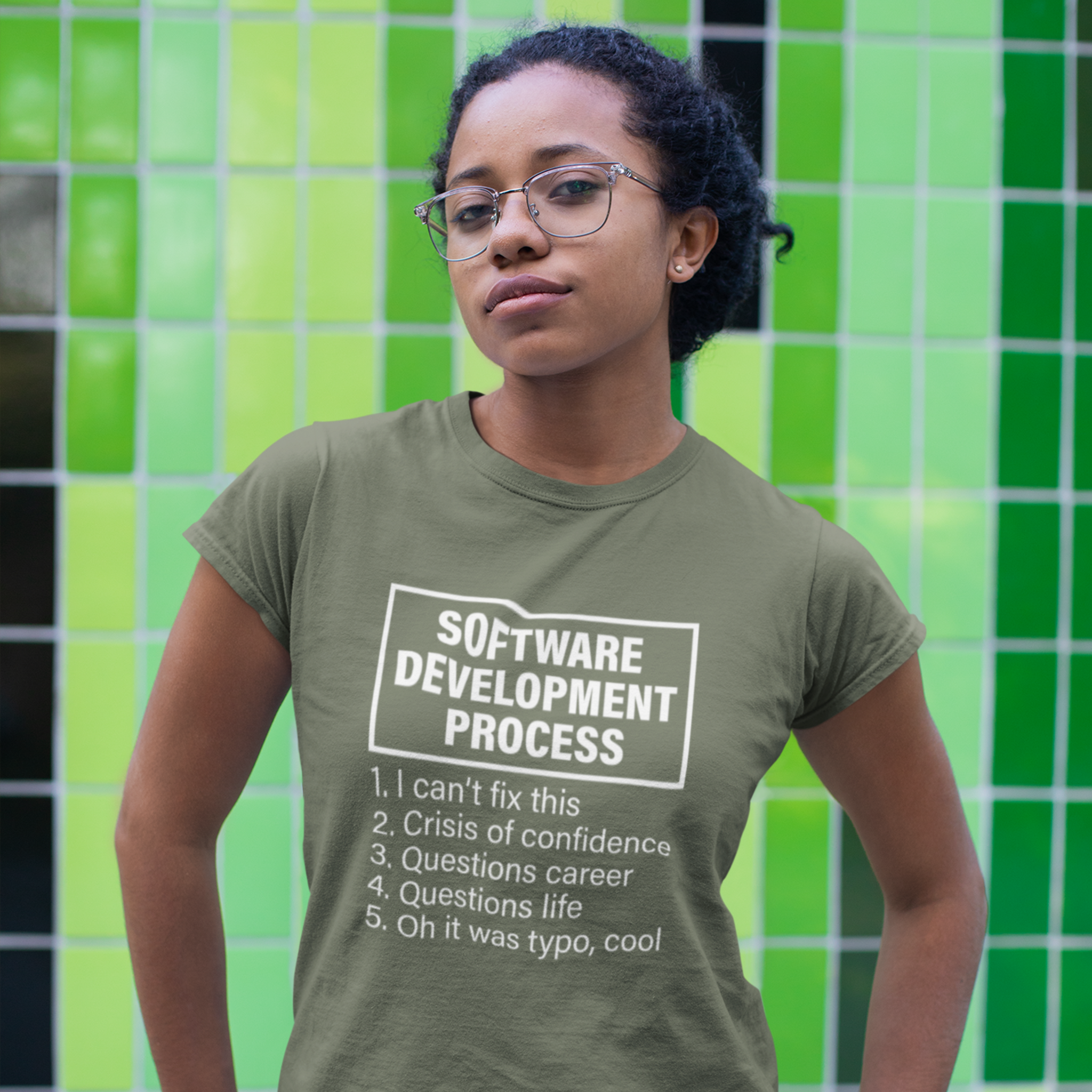 Person wearing a green t-shirt with text in front of a green tiled wall